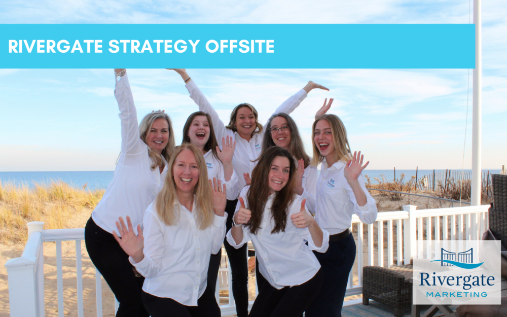 Rivergate Marketing team celebrating on the back porch in front of the ocean.